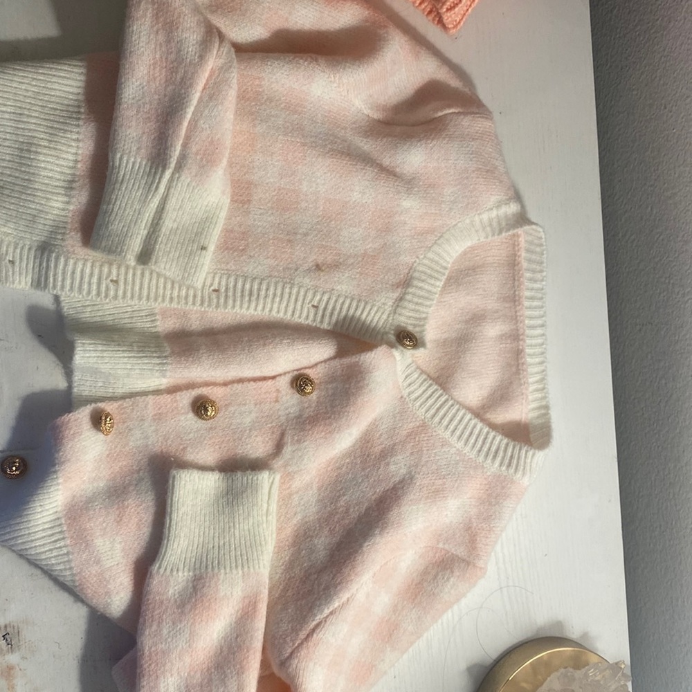 Pink and white tiled sweater with gold buttons.